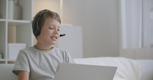 可爱的小男孩正使用笔记本电脑通过互联网与朋友聊天11秒视频