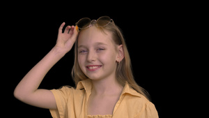 肖像微笑的女孩穿着黄色的裙子戴着黄色眼镜在黑色背景22秒视频