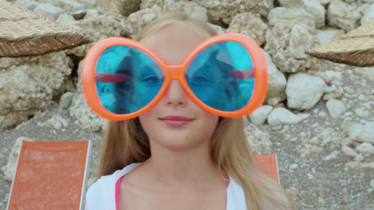 肖像快乐少女在大太阳镜对着镜头微笑面对有趣的女孩在视频
