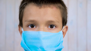 一个戴着蓝色医用口罩看着相机的七岁孩子的脸特写戴防护6秒视频
