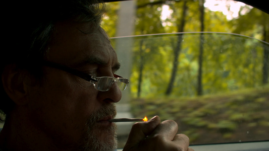 驾驶汽车和吸烟的高级男子肖像视频