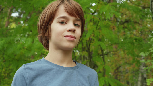 肖像十几岁的男孩在绿叶背景上寻找相机英俊的小男孩在视频