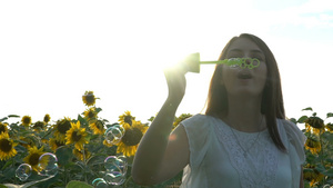 美丽的年轻女孩走在向日葵的黄地上吹吹肥皂泡泡19秒视频