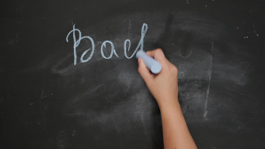 女性手握着蓝色粉笔用黑色粉笔板写回学校视频