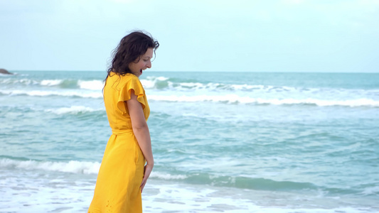 一位身着黄色连衣裙的苗条年轻美丽的黑发女孩在海湾边视频