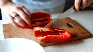 女人用一把锋利的大刀在木制砧板上切红甜椒用天然产品14秒视频