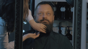 女性理发师用化妆品打理男子的胡须16秒视频