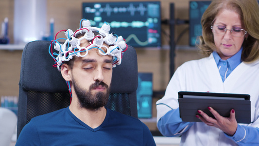 在医生检查大脑活动时闭眼的男性男性患者;检查脑活性视频