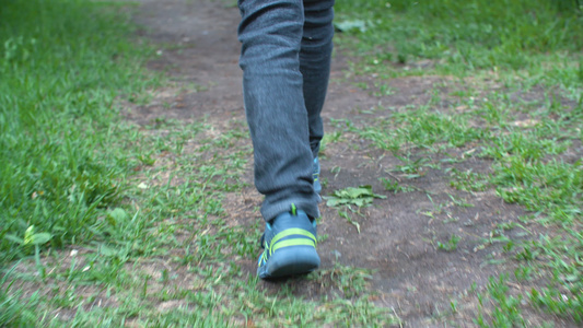 穿着牛仔牛仔裤和运动鞋在路上行走的低层男孩视频