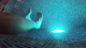 夜间游泳池水下的照明灯光和一双脚25秒视频