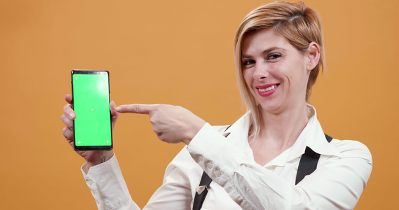 女人用她的手指指着智能手机上面有绿屏视频