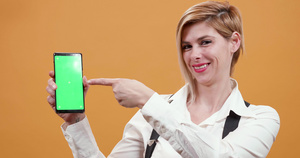 女人用她的手指指着智能手机上面有绿屏9秒视频