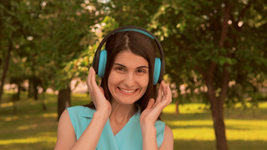 快乐的年轻女性在户外使用耳机视频