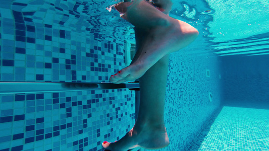 水下射出的女子腿在游泳池中爬上金属梯子视频