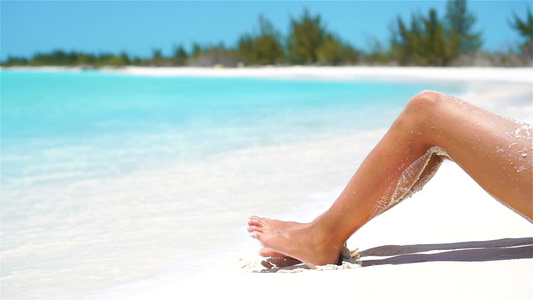 白色沙沙热带海滩上的女性棕色瘦腿视频