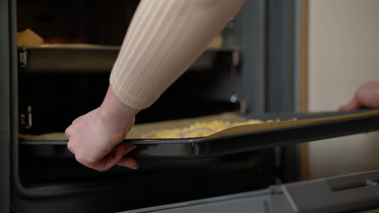 女人亲手把自制披萨放在热烤箱里准备自制披萨的过程视频