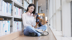 坐在图书馆角落的女大学生正在玩手机14秒视频