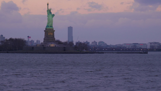 多云的傍晚灯火通明的自由女神像美国纽约市从水中查看视频