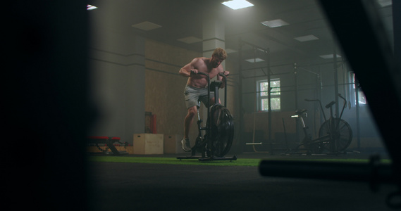 一个坚硬的男子在健身房里固定的自行车上克服疲劳火车视频
