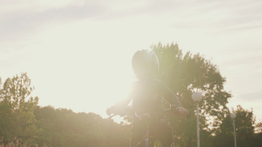 小孩在阳光明媚的秋天骑自行车视频