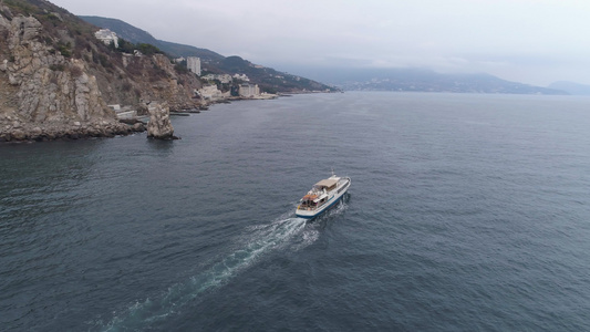 小白色游轮在海岸线附近的海中航行鸟瞰图无人机正在追捕视频