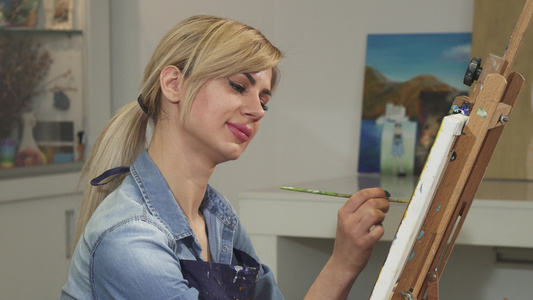 一位美丽的女艺术家在她的工作室微笑着绘画作品的特写视频