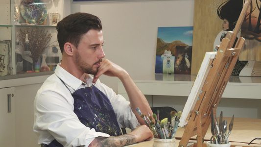 年轻留胡子的男性艺术家检查他的艺术作品思维在工作室视频