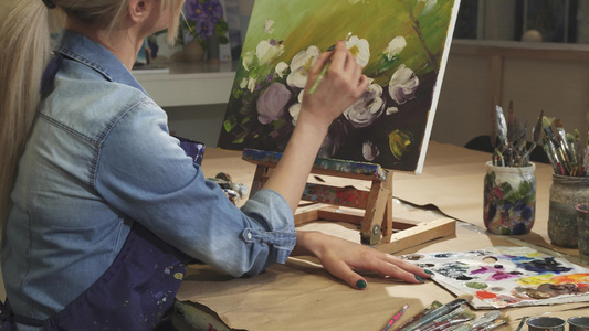 一位微笑的女艺术家在她的艺术工作室画鲜花视频