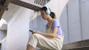 年轻女孩坐在台阶上用手机播放音乐17秒视频