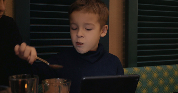 男孩在咖啡馆吃冰淇淋和看平板电脑视频