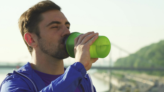 一个英俊的年轻男子在锻炼后喝着饮用水的近身镜头视频