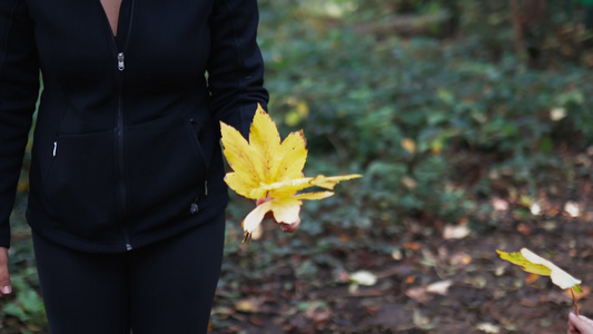 女人在森林的中间持有和指向一些干黄树叶视频