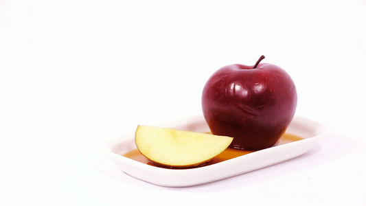 白色盘子上的红苹果和红苹果切片白底的蜂蜜被孤立视频