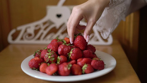 年轻姑娘从盘子上拿红色草莓吃6秒视频