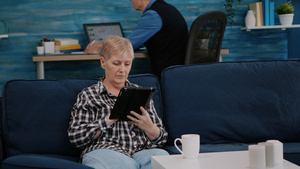 中等年中年老的老年妇女在轻松放松时拿着平板电脑阅读14秒视频