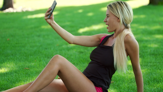 在夏季公园手机上拍自的金发女人视频