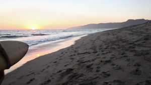 冲浪者在日落时分在海滩上走远的后视图39秒视频