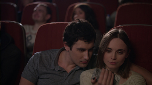 女孩在电影院和男朋友一起在智能手机上自拍视频