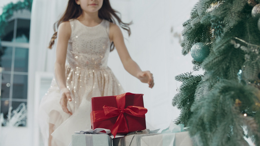 快乐女孩在现代公寓的圣诞树附近 拿着礼物盒视频