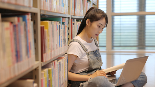 女生一遍查资料一遍写字学习视频