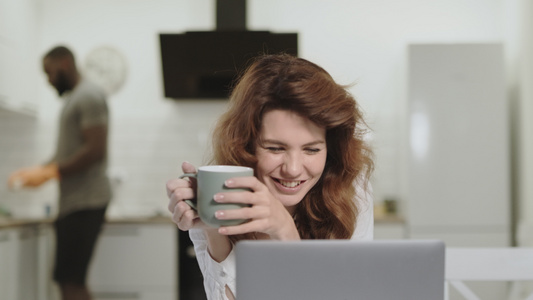 微笑的白人女 在早上厨房的笔记本电脑上读喜讯视频