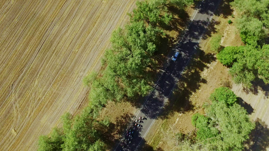 黄色田地风景的农村高速公路上空中观视自行车赛视频