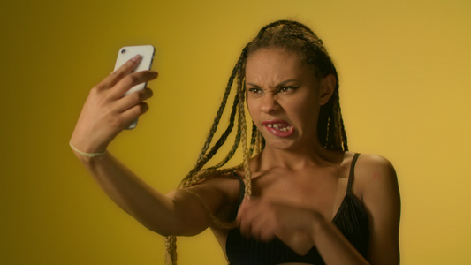 非洲裔美女性在黄色背景下装作没有智能手机的自动拍视频