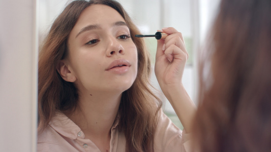 美女人用抹面膏做前浴室镜子的眼睫毛视频