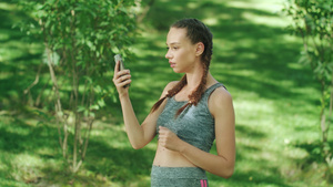 快乐的女跑步者在夏季公园慢跑时在手机应用程序中查看结果10秒视频