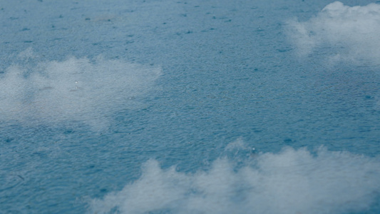 雨滴在清澈的蓝色水面上的特写镜头视频