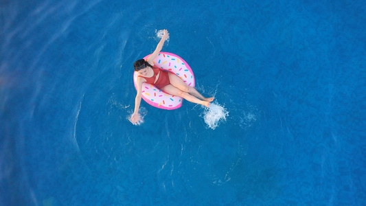 夏日泳池躺在泳圈上的年轻女孩玩水视频