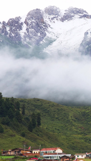 云雾缭绕的雪山脚下小村庄延时视频自驾旅游14秒视频