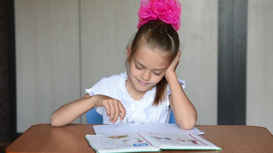 做家庭作业的7岁女学生坐在家餐桌旁做功课视频