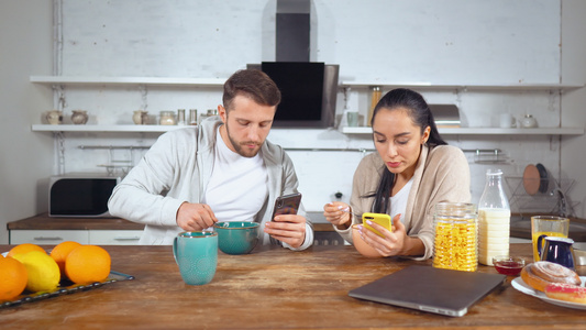 一对夫妇在吃早餐时玩手机视频